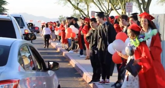 家庭成员和社区荣誉J.O.在毕业典礼上开车时，在人行道上排成六英尺的康姆斯高中毕业生。照片由J.O.梳区